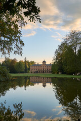 Fototapeta na wymiar Rastatt Favorite Palace and idyllic palace garden with trees reflecting in pond at sunset