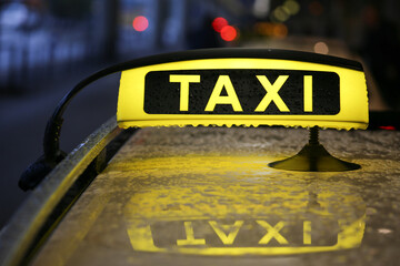 Taxi sign on yellow cab on rainy day