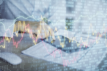 Double exposure of man's hands holding and using a digital device and forex graph drawing. Financial market concept.