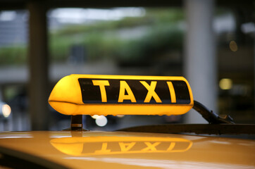 Taxi sign on yellow cab on rainy day