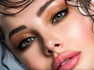 Closeup portrait of a beautiful young woman with brown gkamour makeup. Model looking at camera..