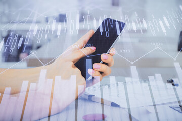 Double exposure of man's hands holding and using a digital device and forex graph drawing. Financial market concept.