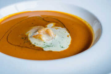 a plate of lobster bisque decorated with a dollop of cream and small shrimps