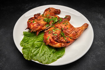 Fried chicken with a delicious crispy crust, with lettuce, on a white plate, on a black background