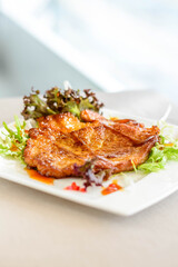 main course of Pan-fried Pork Chop with Soy Sauce served on lettuce on a white plate