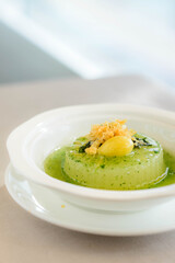 main course of Simmered Winter Melon in Spinach Sauce topped with a gingko nut served in a white bowl