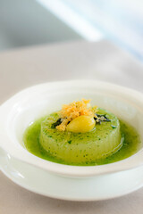 main course of Simmered Winter Melon in Spinach Sauce topped with a gingko nut served in a white bowl