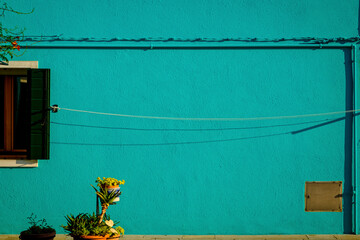 Turquoise background showing a brightly painted facade of a traditional Burano house 