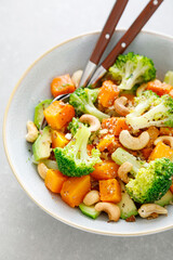 Vegetable salad bowl of broccoli, baked pumpkin, avocado and nuts. Healthy vegan food