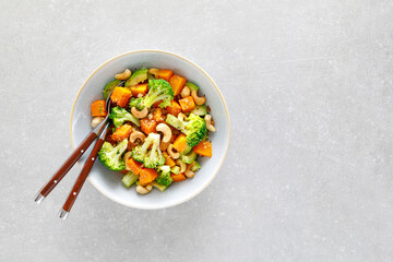 Vegetable salad bowl of broccoli, baked pumpkin, avocado and nuts. Healthy vegan food