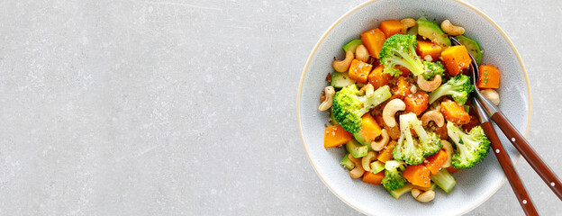 Vegetable salad bowl of broccoli, baked pumpkin, avocado and nuts. Healthy vegan food