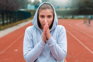 It is so cold today. Young woman warming up her hands while standing.