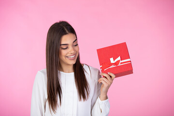 Happy woman holding a gift box isolated on pink background. Beautiful happy woman holding gift box. Birthday or Valentine`s day celebrating concept