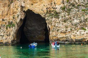 A boat with tourist about to enter the cave which is the exit for the Inland Sea Gozo..