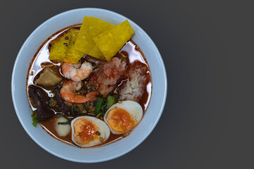 Top view of Noodle Tom Yum Sea Food with Boiled eggs. With shrimp and fried dumplings. On gray background.