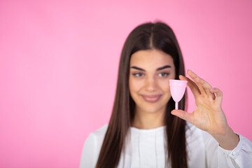 Happy Young woman Holding a Silicone Menstrual Cup. Young woman holding different types of feminine hygiene products - menstrual cup. Gynecology concept