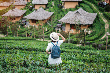 Happy tourist woman in white dress enjoy beautiful Tea garden.Traveler visiting in Ban Rak Thai village, Mae Hong Son, Thailand. travel, vacation and holiday concept