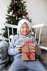 Obraz na płótnie Canvas Happy boy in santa clause hat with Christmas gifts