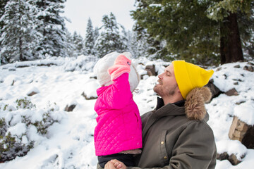 Happy father and daughter smiling in a snowy forest