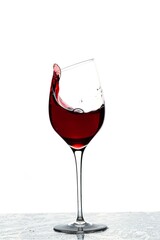 Close up view of splashing red wine in glass isolated on white background. 