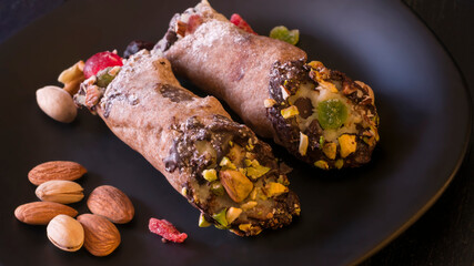 A close view of two cannoli on a black plate, A traditional italian dessert