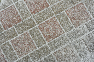 The first snow on the tile-paving stones, the material is an abstract background.