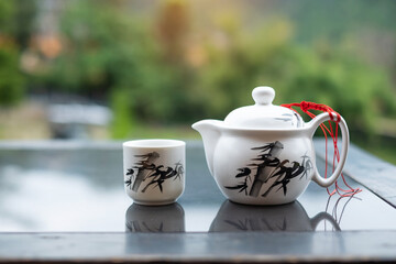 teapot and hot tea to cup on wood table against tea garden view background in the morning, Ban Rak Thai village, Mae Hong Son province, Thailand
