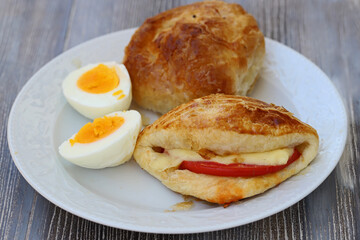 One piece of izmir boyoz, tomato cheese pie and egg in white plate