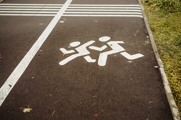white drawn children sign on bike path near playground.
