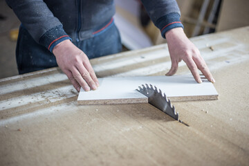 Close-up of a wooden cutting table with an electric circular saw. Professional carpenter cutting a wooden board at a sawmill. Sawing machine