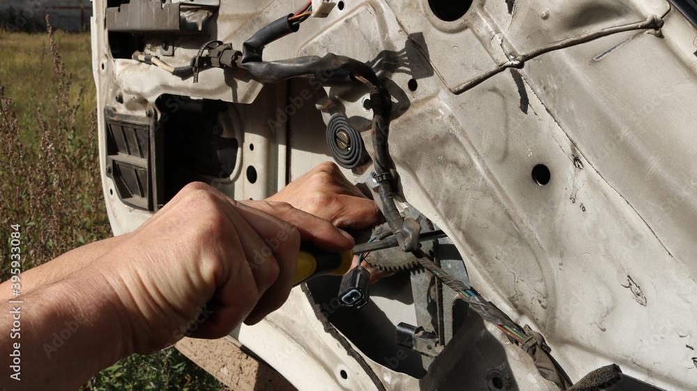 Wall mural manual repair using an electrician screwdriver in the structure of the door of the truck in the open