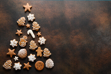 Obraz na płótnie Canvas Christmas holidays homemade cookies arranged as tree on dark brown background. Xmas greeting card with copy space. View from above. Flat lay.