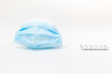 Closeup of protective mask and blister of tablets on white