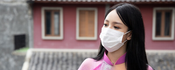 Banner of young Asian Vietnamese woman properly wearing face mask in outdoor public space