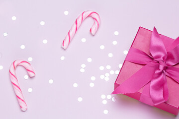Obraz na płótnie Canvas Pink gift with candy cane and silver confetti. Copy space for advertising. Concept to celebrate and to congratulate.