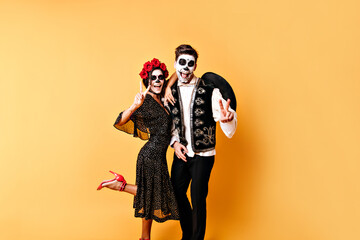 Funny shot of full-length couple of lovers in halloween costumes having fun against backdrop of...