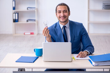 Young male employee holding lamp in the office