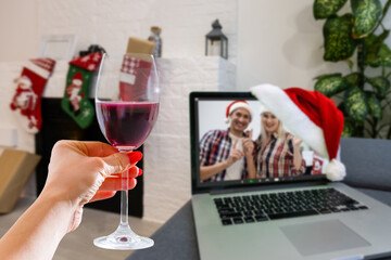 Happy woman making a toast on video call celebrating christmas with glass of wine online during coronavirus outbreak - Focus on wine glass