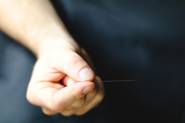 close up of a hand holding an acupuncture needle horizontally 