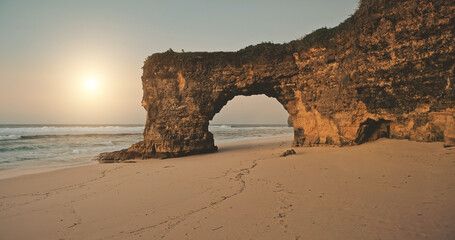 Aerial view of sun over rock wall with hole at sand beach sea shore. Unique geological formation at Bawana Beach, Sumba Island, Indonesia, Asia. Nobody nature landscape with ocean water waves © Goinyk