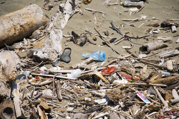 Śmieci wyrzucone na brzeg podczas z oceanu podczas odpływu. Widoczna plastikowa butelka, opakowania jednorazowe i podeszwa buta. - obrazy, fototapety, plakaty