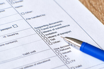 Application form for a Schengen visa. The form and pen are on the table.