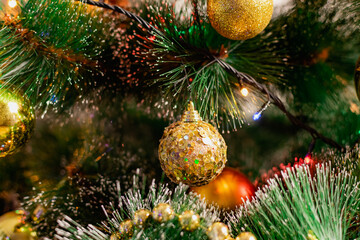 Obraz na płótnie Canvas Golden Christmas decorations on a green artificial Christmas tree. Making a festive Christmas. Funny cute toys and gifts on the branches