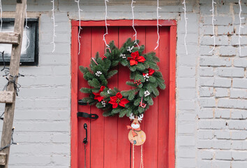Fototapeta na wymiar Red wooden door decorated with Christmas wreath.