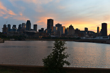 Obraz premium Montreal Downtown skyline at the time between sunset and twilight. Reflections of sun rays on Saint Laurent river.