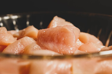 Raw chicken meat slices close up in a plate.