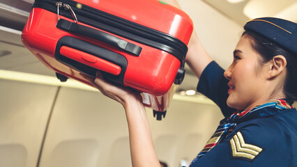 Cabin crew lift luggage bag in airplane . Airline transportation and tourism concept.