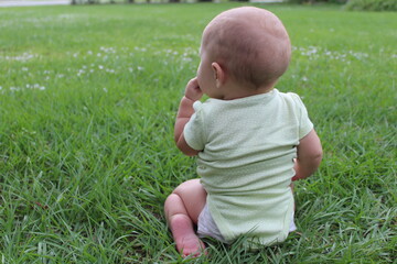 A young baby exploring and learning her surroundings in the grass outside.
