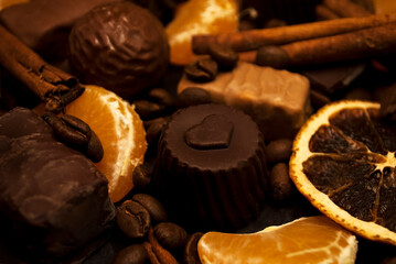 Various spices, chocolate and coffee beans, mandarin slices on a dark background. Christmas background.