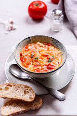 Vegetarian spicy tomato rice soup on grey concrete background. Selective focus